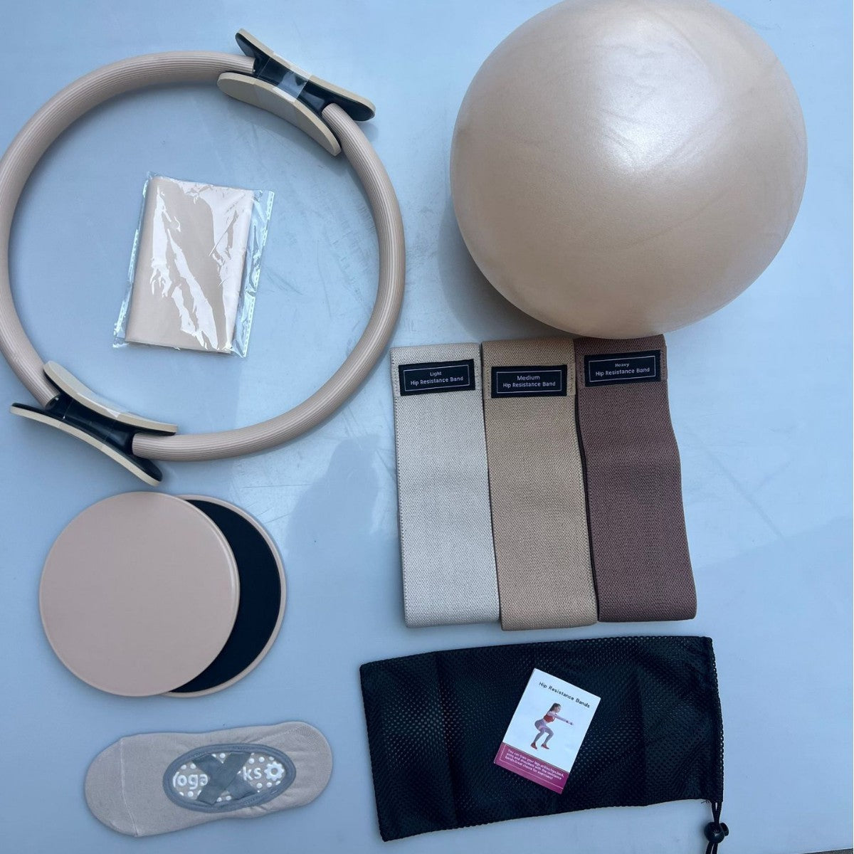 Home Pilates Essentials Kit in Sand: Pilates ring, mini ball, three fabric bands, stretch band, core sliders, grip socks and bag